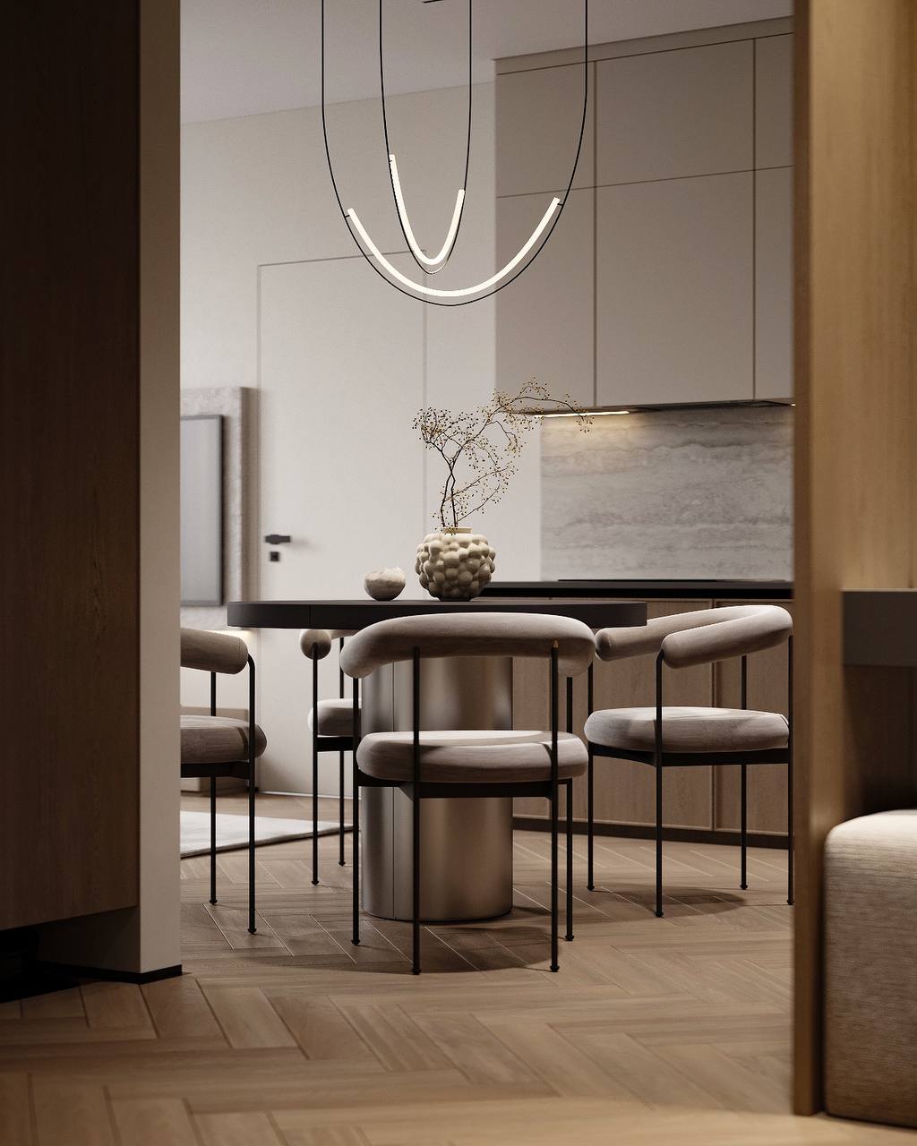 A view from the entrance toward the round dining table, upholstered chairs and kitchen cabinetry.